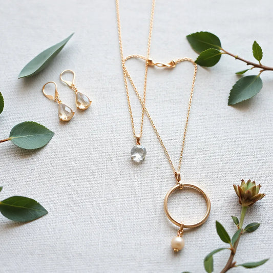 A set of elegant earrings, necklace, bracelets, and a ring styled on neutral fabric