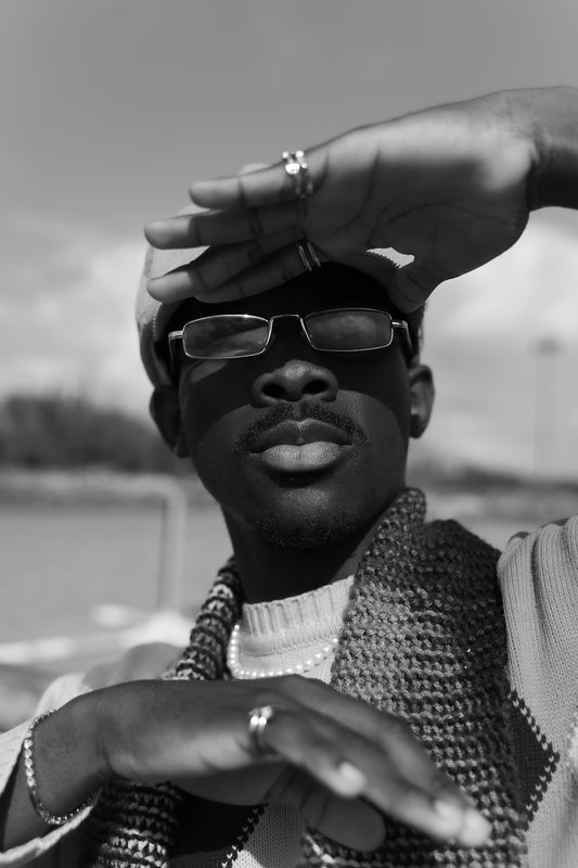 Man wearing glasses and hat shields eyes from sun