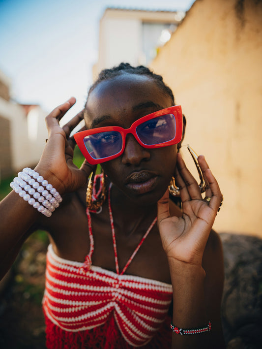 Young woman with red sunglasses and jewelry.