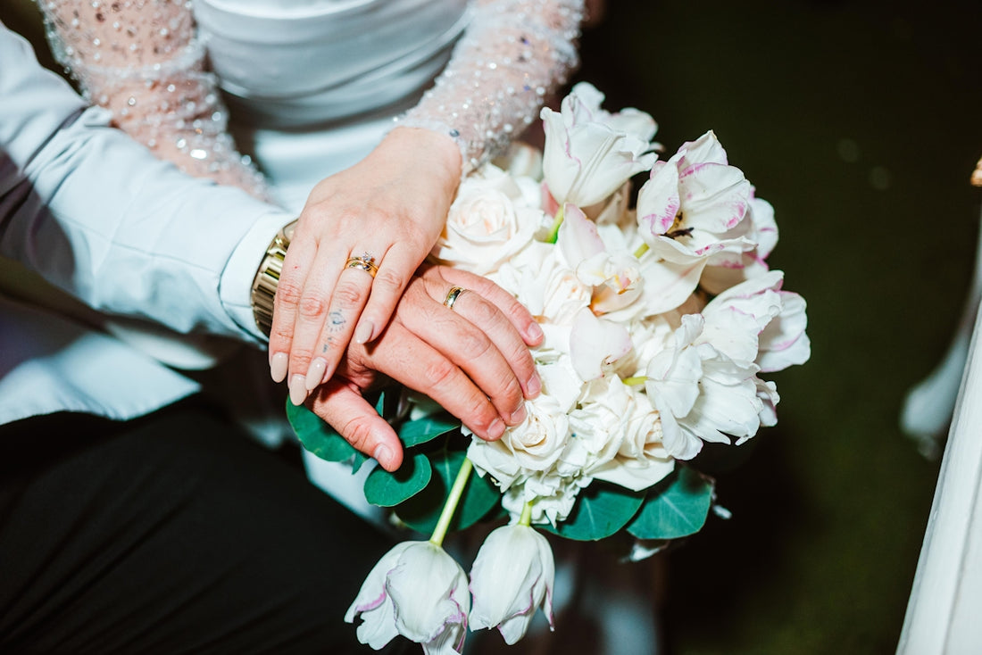 Bride and groom's hands resting on wedding bouquet