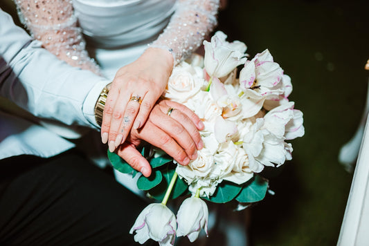 Bride and groom's hands resting on wedding bouquet