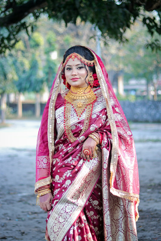 A bride in a traditional maroon and gold sari